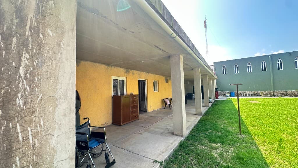 A sunny community walkway beside a yellow building and lawn — the kind of everyday setting where Nuestro Pueblo Valle outreach takes place.