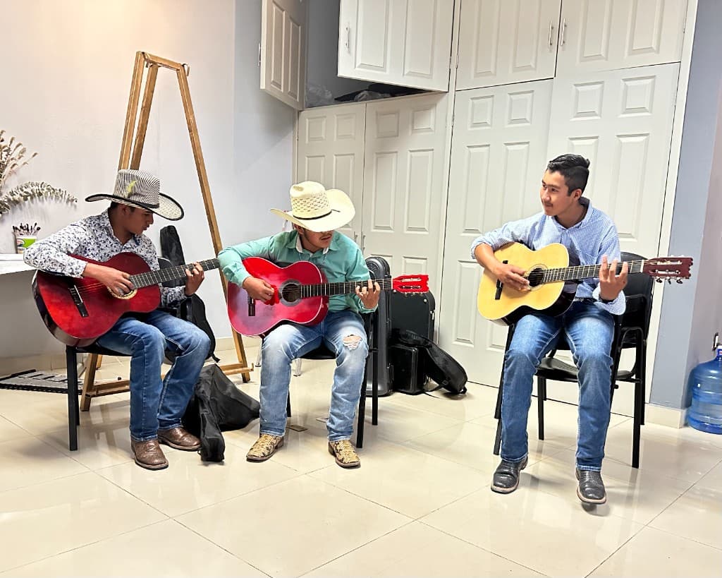 Young people in a community music session with acoustic guitars — arts programming supported through local outreach.