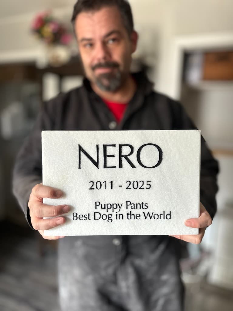 A finished personalized marble pet memorial held with care — the kind of meaningful piece our family brands help create.